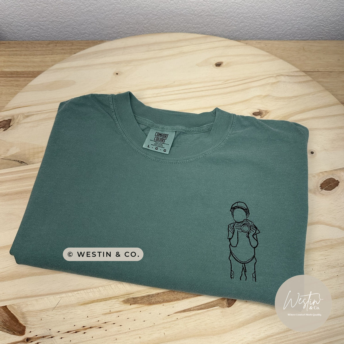Custom embroidered line art portrait of a child holding a camera on a green Comfort Colors tee