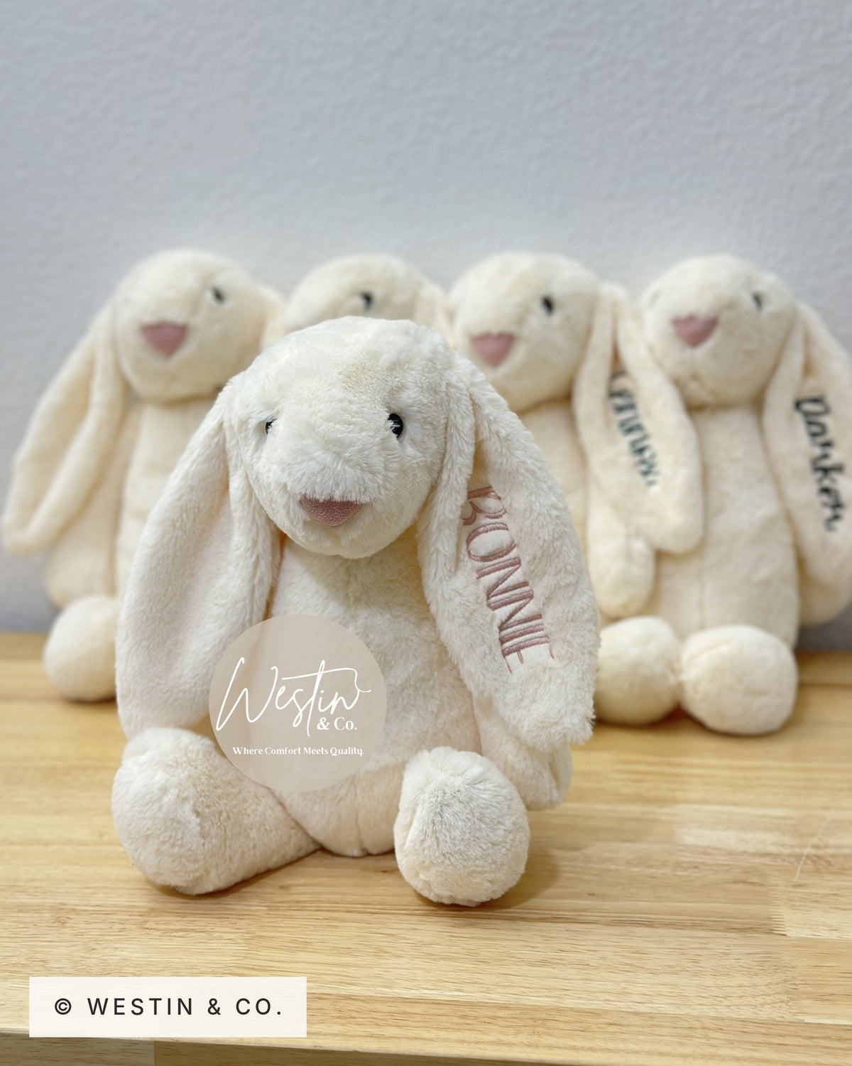 Ivory embroidered plush bunny in front of a row of personalized bunnies
