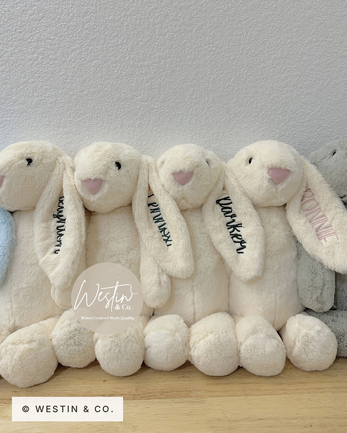Row of ivory plush bunnies with names embroidered on their ears